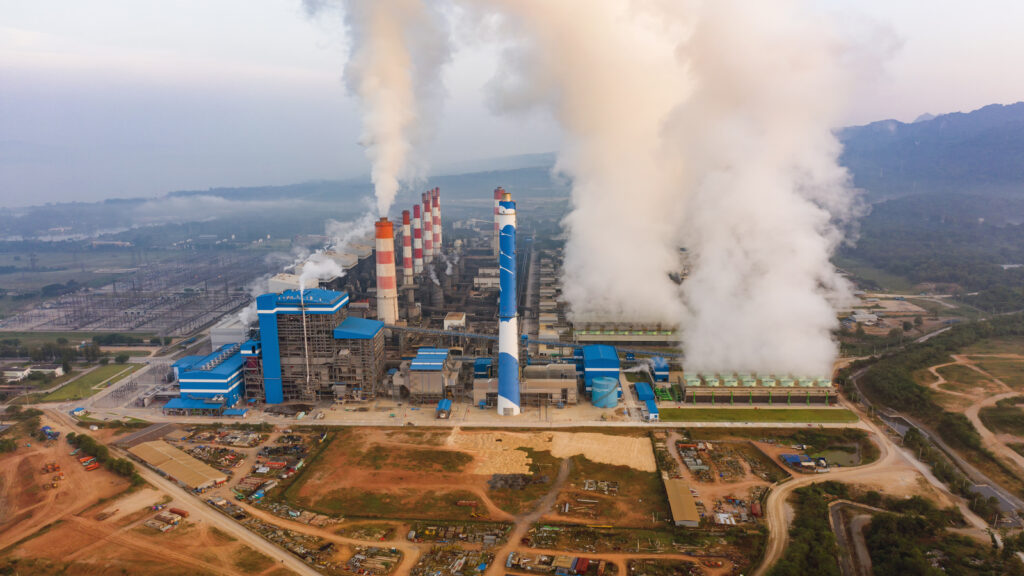 Indústria ao entardecer com emissão de diversos gases.