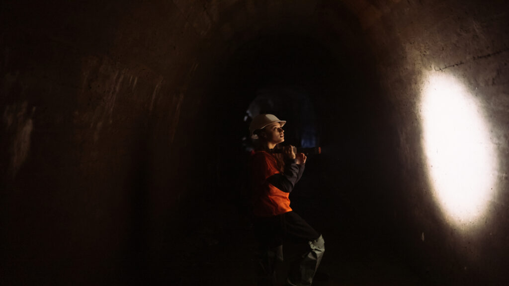 Mulher utilizando lanterna antiexplosao em tunel